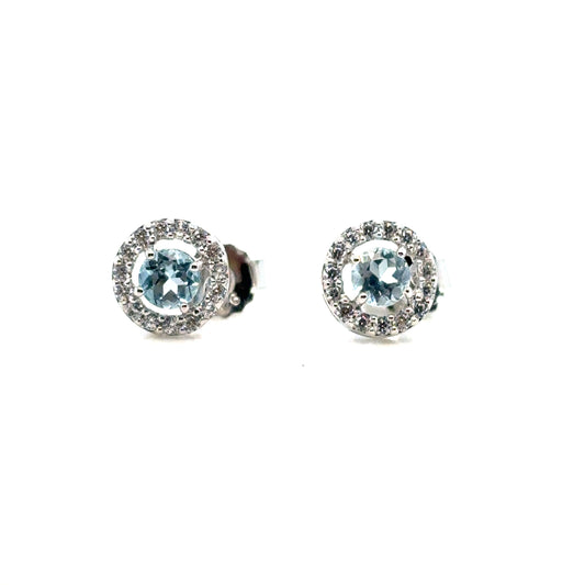 Round Sky Blue Topaz Halo Stud Earrings Set In Sterling Silver With Cubic Zirconia